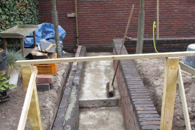 Storten beton en opmetselen van de vijvermuren voor een strakke vijverbak. De vijver word gepolyesterd